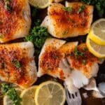 flaky baked cod on a baking sheet with lemons