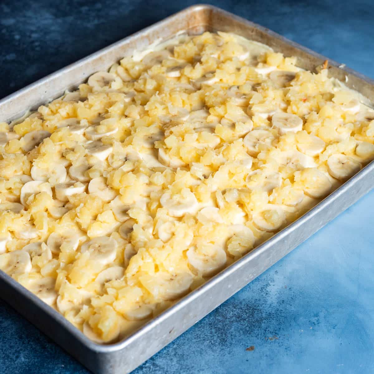 pineapple and bananas over yellow cake in a pan