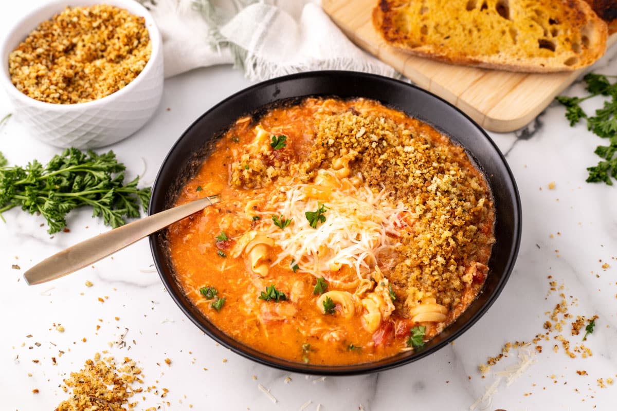 a bowl of chicken parmesan soup with cheese and breadcrumbs