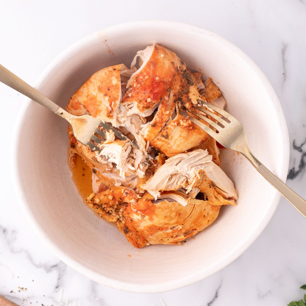 seasoned cooked chicken in a bowl with two forks