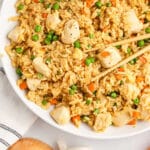 a plate of chicken fried rice with chopsticks