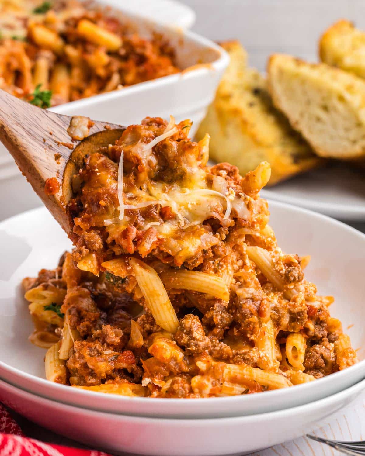 spooning a pasta casserole onto a plate