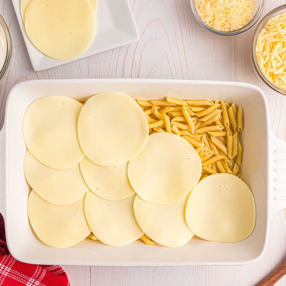 pasta in a baking pan with slices of cheese over the top