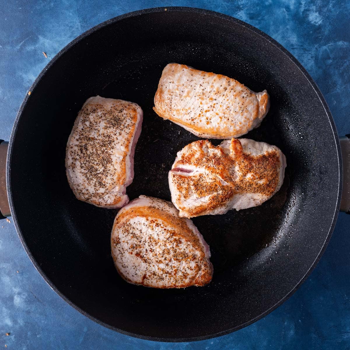 browned pork chops in a black skillet