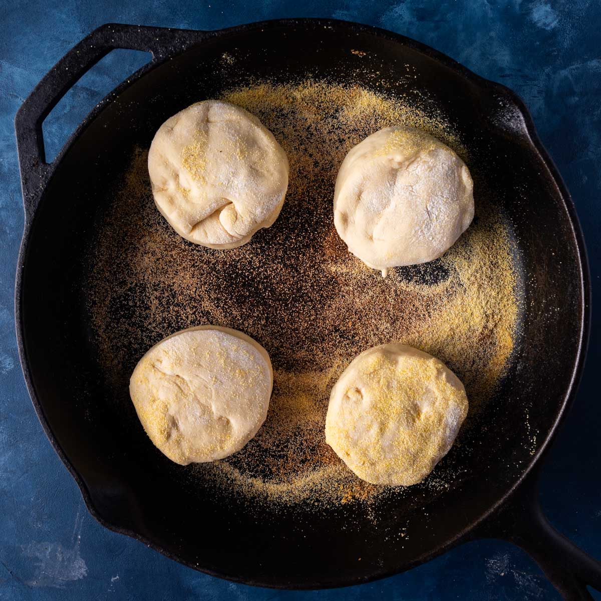 uncooked english muffins in a cast iron skillet