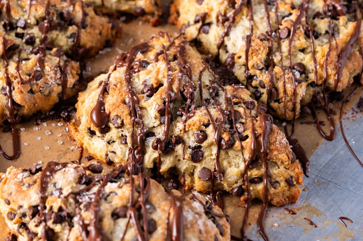 closeup of chocolate drizzled sourdough discard scones on a baking sheet