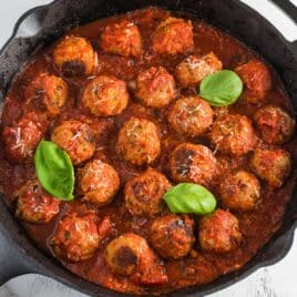 turkey meatballs in a skillet with spaghetti sauce and basil