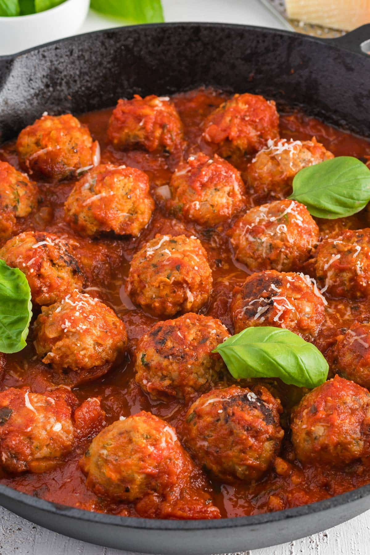 Italian turkey meatballs in a skillet with spaghetti sauce and basil