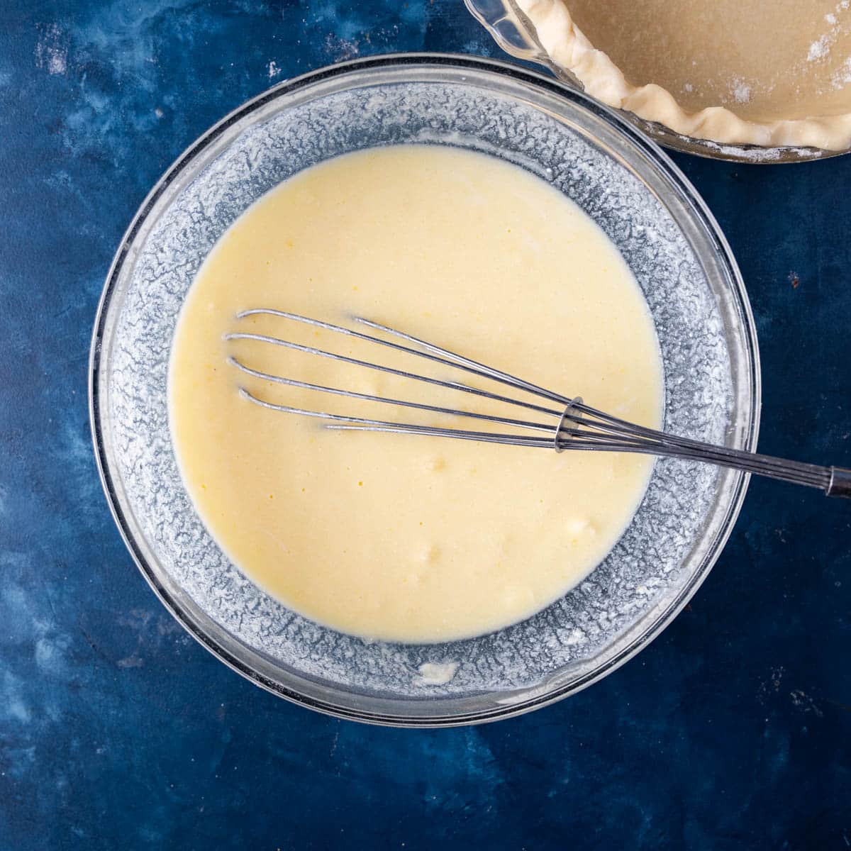 mixture for buttermilk pie in a bowl with a whisk