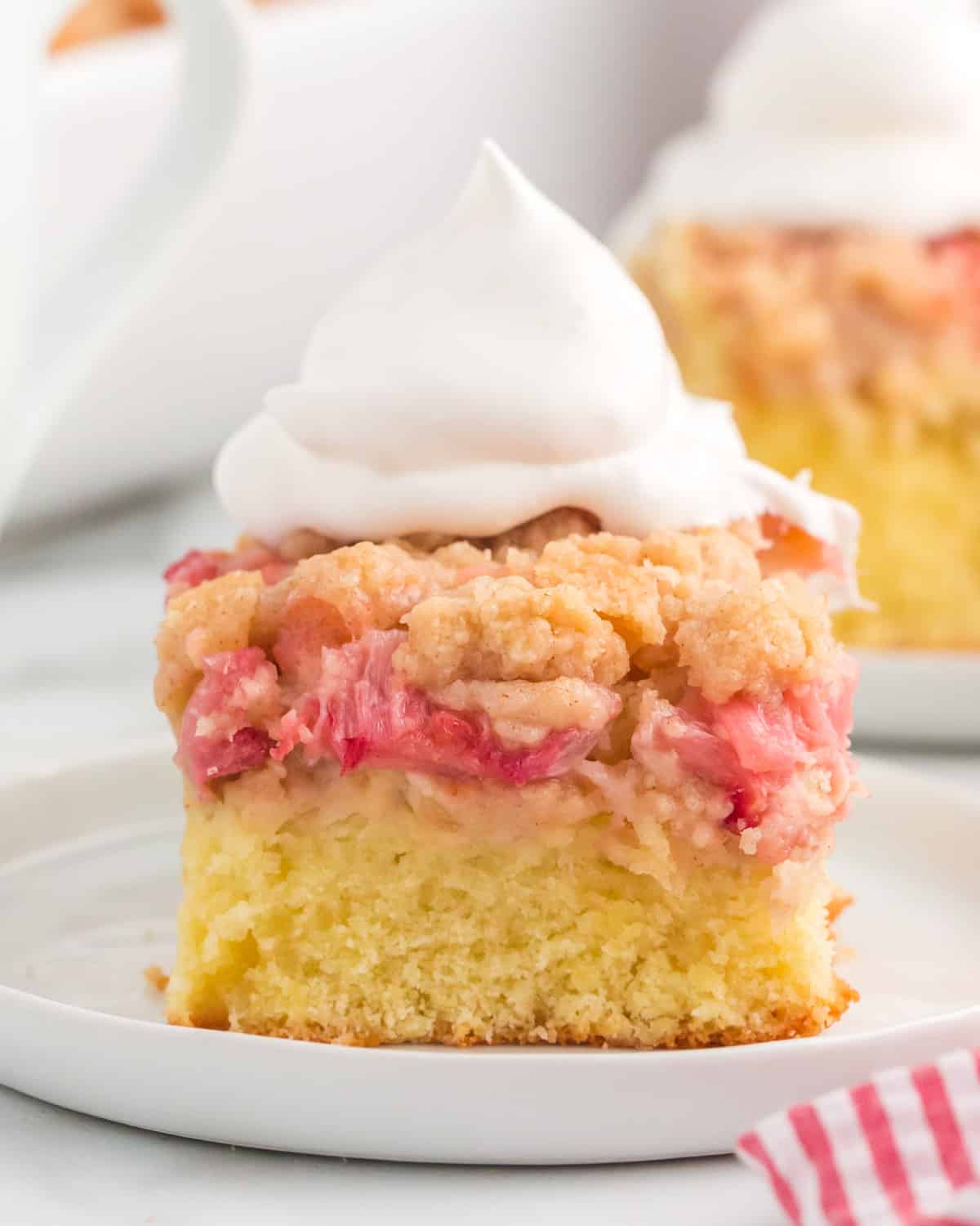 a piece of rhubarb coffee cake with a dollop of whipped cream