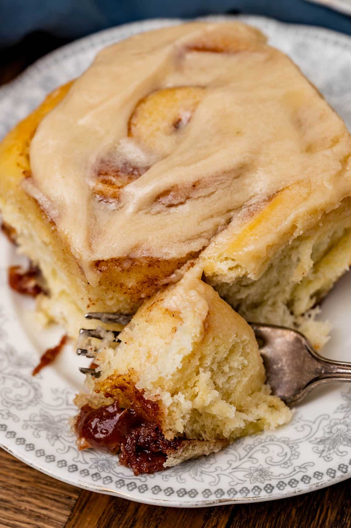 a cinnamon roll on a plate with one bite on a fork